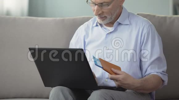 60岁的男子观看度假小镇的照片用笔记本电脑预订酒店房间视频的预览图