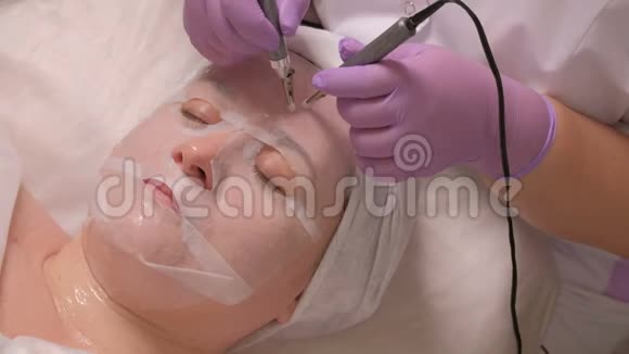使用电器进行面部按摩的化妆程序一个戴着白色面具的女人在医疗办公室这就是视频的预览图