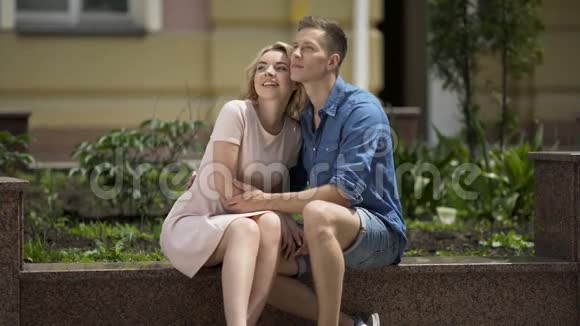 浪漫的夫妻坐在长凳上女孩亲吻她的男朋友的脸颊感情视频的预览图
