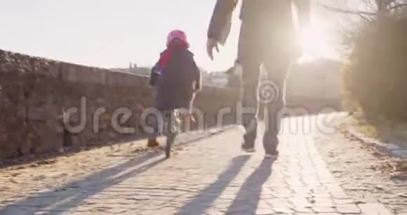 女儿女儿女孩学习骑冰柱与爸爸在城市教学成长童年活跃安全家庭人行道视频的预览图