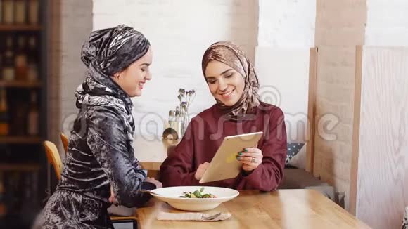 女穆斯林大学生使用平板电脑在咖啡厅视频的预览图