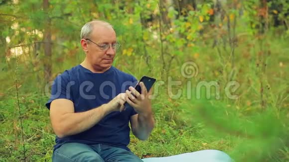 森林里一个戴眼镜的人坐在草地上用信使传达信息视频的预览图