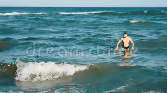 年轻的帅哥挥舞着海藻杂草植物海滩碧水环境地球海浪阳光视频的预览图