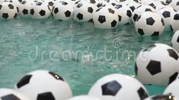 许多黑白足球背景足球球在纯净水中游泳雨水从高空落下视频的预览图