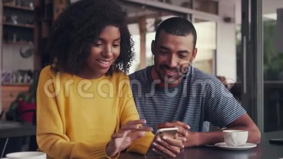 年轻夫妇坐在咖啡馆里看手机视频的预览图