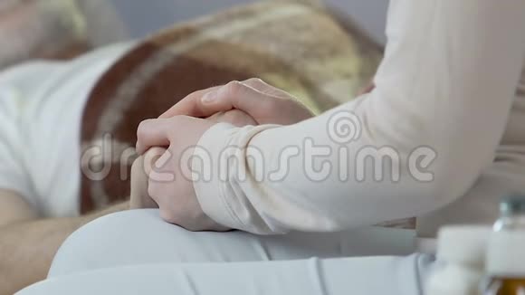 坐在床沿上的女人用手牵着老人临终的舞台临终的床视频的预览图