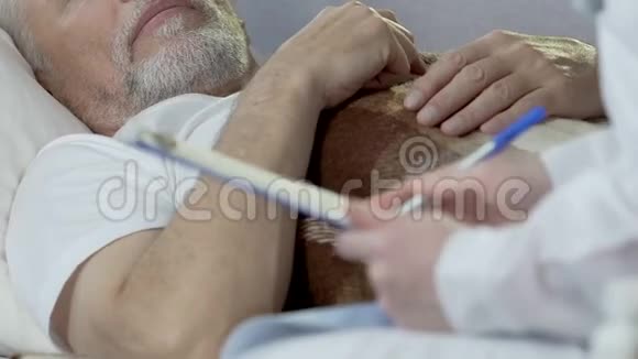 坐在躺在床上的老人旁边的待命医生写下症状视频的预览图