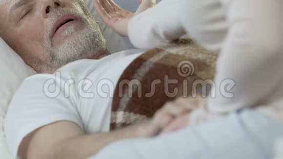 女人坐在床边手牵着老人照顾他视频的预览图
