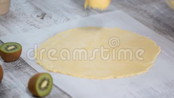 女性的手在生面团上涂上奶油用新鲜的猕猴桃做厨房视频的预览图