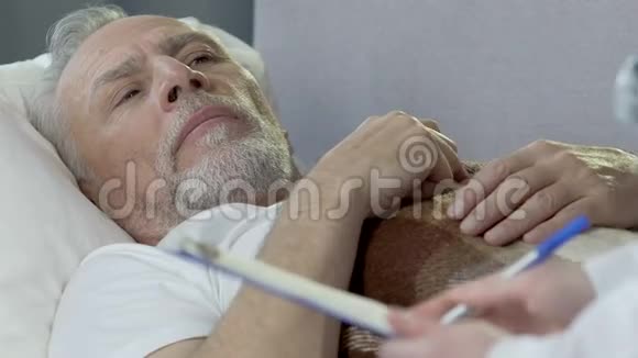 老人躺在床上和坐在他旁边的医生说话救护车视频的预览图
