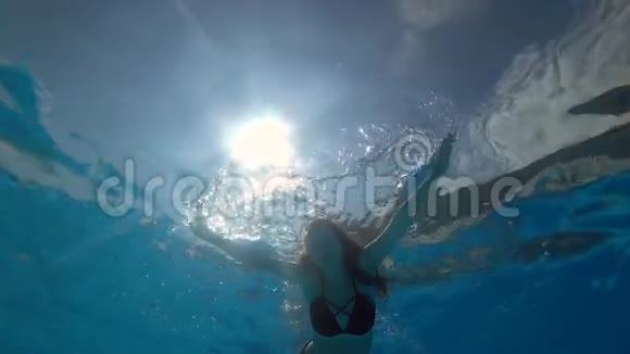 在干净的蓝色游泳池里的女人在充满活力的环境中在背景气泡上睁开眼睛在水下游泳视频的预览图