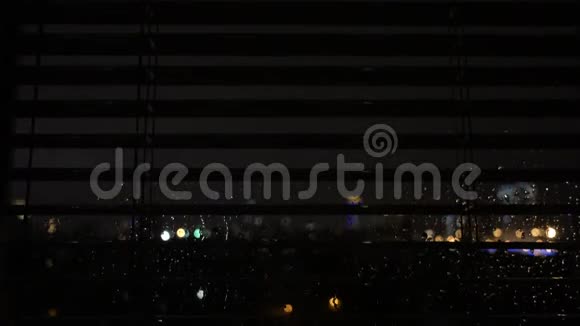 夜晚城市背景下玻璃上的雨滴视频的预览图