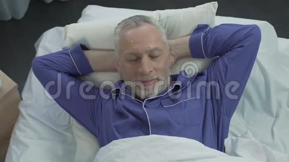 老人在床上沐浴在新的矫形床垫上享受舒适的睡眠视频的预览图