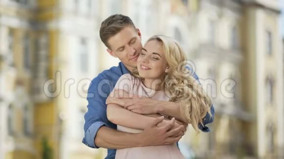 年轻人从背后拥抱女朋友亲吻她的手和脸颊相爱视频的预览图