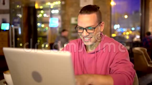 迷人的西班牙裔男子与美丽的微笑使用笔记本电脑在咖啡馆技术概念戴眼镜的人视频的预览图