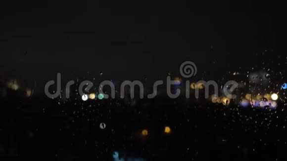 夜晚城市背景下玻璃上的雨滴视频的预览图