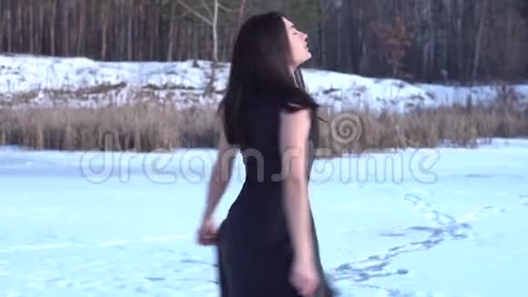 一幅美丽迷人的微笑着的年轻黑发女孩在森林景观背景上穿着黑色连衣裙转身视频的预览图