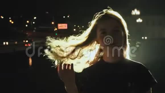 女孩肖像剪影头发在微风中挥动在夜间城市背景城市灯光中的轻发火灾视频的预览图