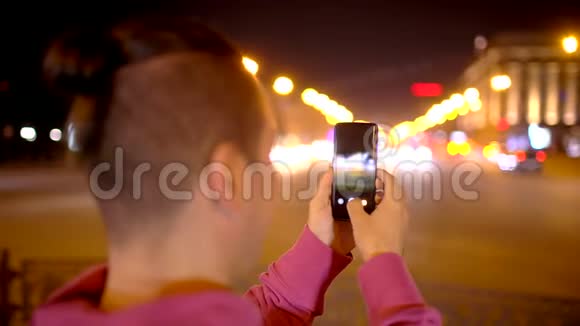 在夜城用相机拍照的人年轻的休闲男子在外面用相机手机拍照视频的预览图