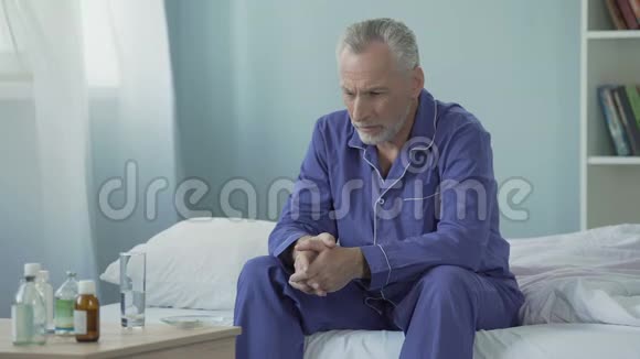 坐在床上服用药物以恢复病情令生病的老人心烦意乱视频的预览图