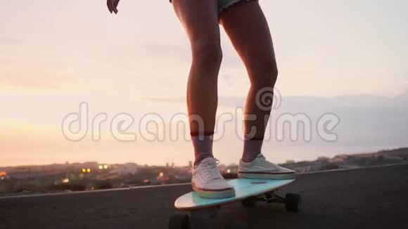女孩骑着滑板在海洋附近和一座大山缓慢运动健康的生活方式运动视频的预览图