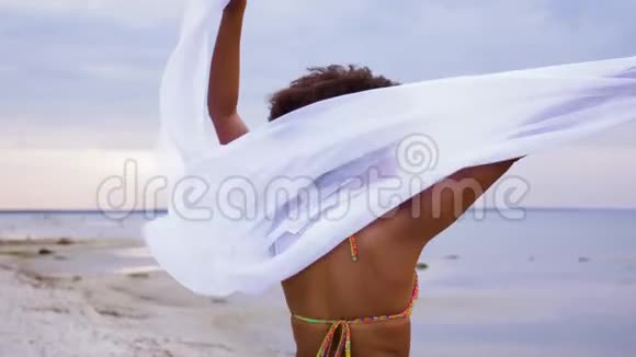 穿着披肩的非洲女人在沙滩上迎风招展视频的预览图
