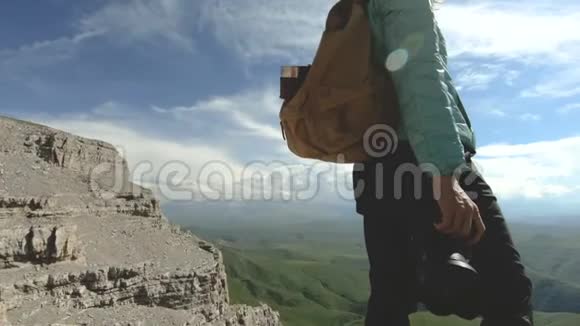 一位手中拿着数码相机的摄影师的腿女孩的特写镜头正站在岩石高原上视频的预览图
