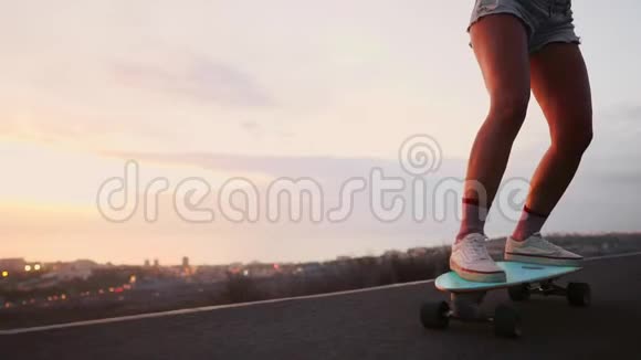女孩骑着滑板在海洋附近和一座大山缓慢运动健康的生活方式运动视频的预览图