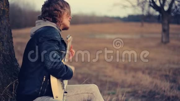 日落时演奏吉他的男音乐家视频的预览图