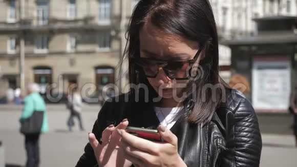 女人在城市街道上的智能手机上搜索信息技术和生活方式理念视频的预览图