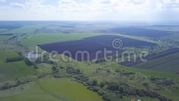 空中无人机可以看到犁地和绿色的田野树木背景是蓝色多云天空的小镇农业视频的预览图