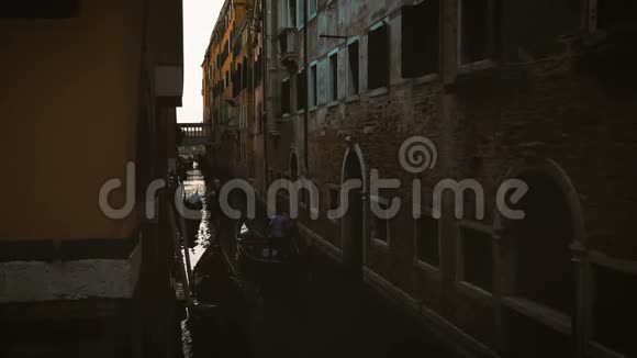 傍晚时在威尼斯的一条狭窄的河道里漂浮着贡多拉斯视频的预览图