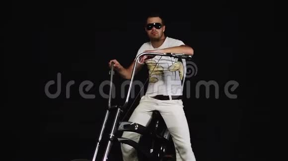 戴墨镜的白衣男子坐在自行车上手握车把视频的预览图