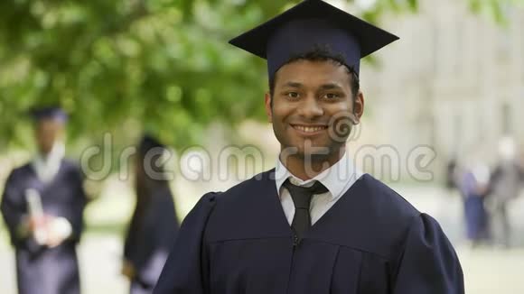 毕业时穿着学术服装戴着戴着文凭和拇指的帽子受过教育视频的预览图