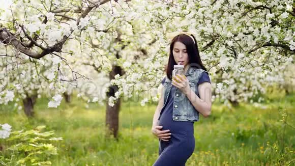 怀孕的女孩在户外喝橙汁视频的预览图