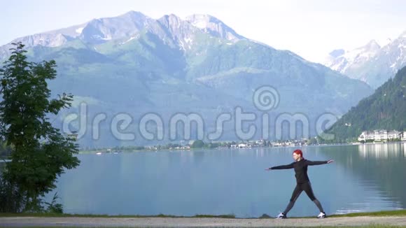 一位迷人的年轻女子在做一个瑜伽姿势以保持平衡并在Zellam湖附近伸展视频的预览图
