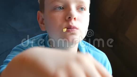 蓝眼睛帅哥少年在餐馆吃炸薯条快餐垃圾食品视频的预览图