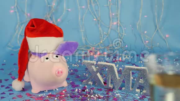 软玩具粉红色的猪戴着红色圣诞老人帽子背景是一棵蓝色的圣诞树上面写着视频的预览图