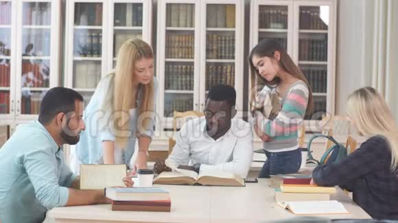 各种不同种族的学生用旧书在图书馆度过闲暇时光视频的预览图