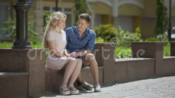两个人坐在长凳上第一次约会时拥抱害羞的女孩浪漫的心情视频的预览图