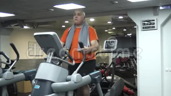 有趣的胖子在健身房做椭球运动视频的预览图
