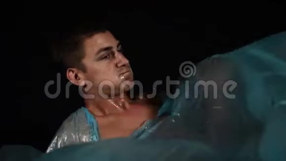 年轻人躺在蓝色玻璃纸电影里模仿海浪把水喷到镜头上视频的预览图