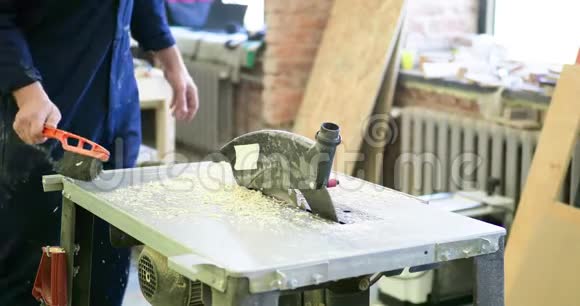木工车间的一个人从机器上扫出锯末和刨花视频的预览图