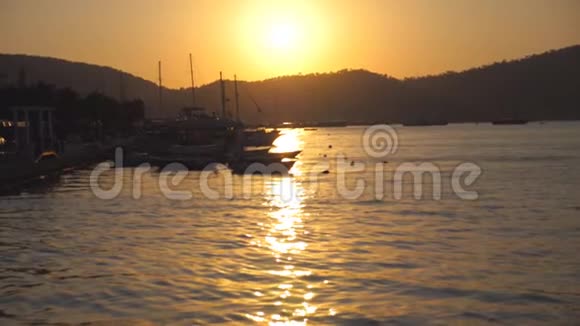日落时分在海滨附近的渔船剪影在美丽的夜晚渔人的船只在海浪中摇曳视频的预览图