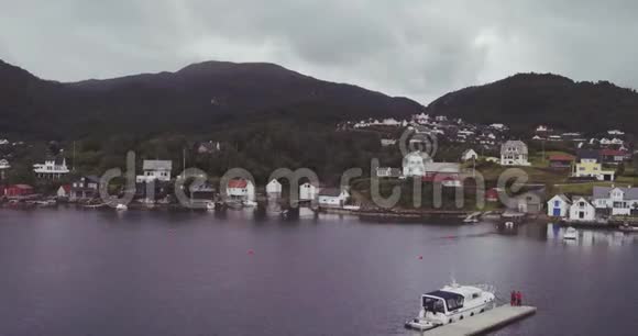 在峡湾沿岸由山丘组成的有游艇棚的村庄视频的预览图