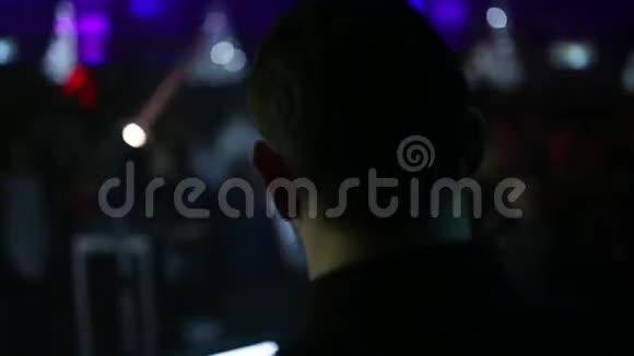 特写DJ的头像从后面在模糊的背景下人们在聚会上跳舞DJ在派对上工作视频的预览图