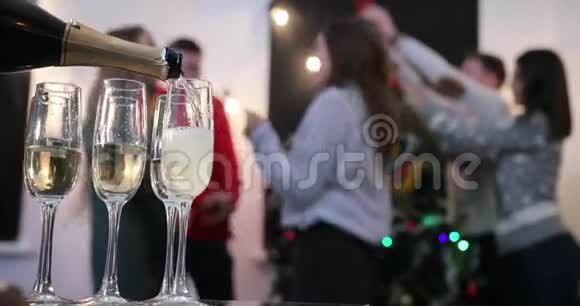 新年庆典当年轻人在圣诞节前在背景上跳舞时他会在杯子里倒香槟视频的预览图