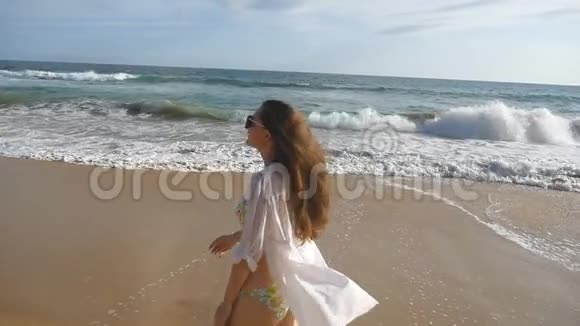 穿比基尼和衬衫的快乐女人在海边散步举起双手年轻美丽的女孩享受生活视频的预览图