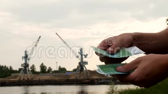 一个人在港口生产河沙的货物起重机和收据的背景下计算货币欧元视频的预览图