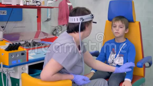 一个男孩坐在医生办公室鼻子里有棉签视频的预览图